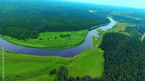 Aerial view of lush green forests and winding river under bright daylight in summer