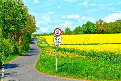 Φωτογραφία Idyllischer Fahrradweg am blühenden Rapsfeld mit Verkehrsschild, Gründau, Hessen