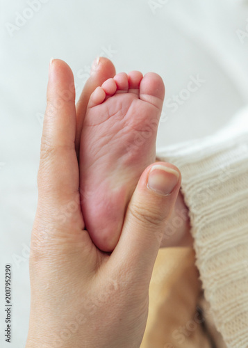Mother holding newborn baby feet close up