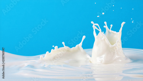 Foto Milk splashes in water against bright blue background, dynamic liquid motion