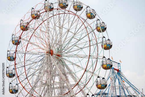 Colorful Ferris Wheel with Vibrant Gondolas and Intricate Metal Framework Against Clear Blue Sky
