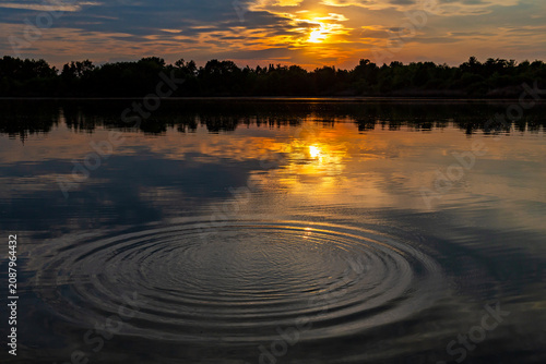 Ripples in a lake reflecting a colorful sunset at Fountain Lakes Park in St. Charles, Missouri 