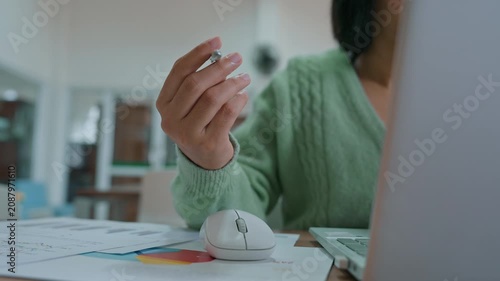 Close up of businesswoman spinning pen and working from home on laptop.