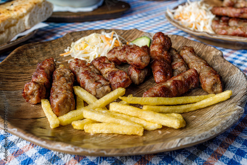 Obraz na plátně Cevapi served with fries and salad on a wooden plate at a local eatery during lu