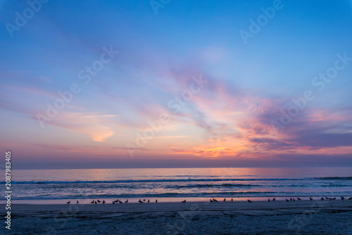 dramatic photograph of an Atlantic coastal sunset, showing a dark, turbulent sea beneath a colorful sky