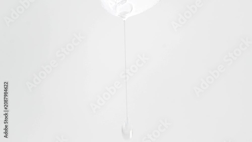 Drops of transparent cosmetic texture dripping, neutral background with minimalist composition.