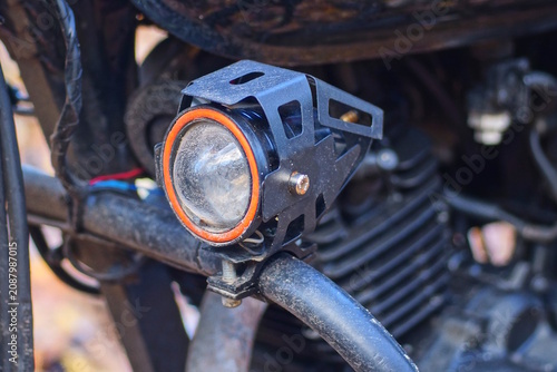 one small white glass headlight turn signal in a black metal housing on a motorcycle on the street