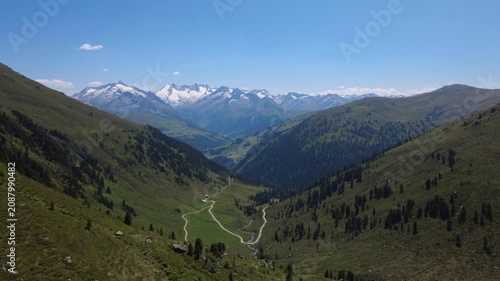 Aerial View of a Lush Green Valley with Snow-Capped Peaks in the Austrian Alps during Summer.