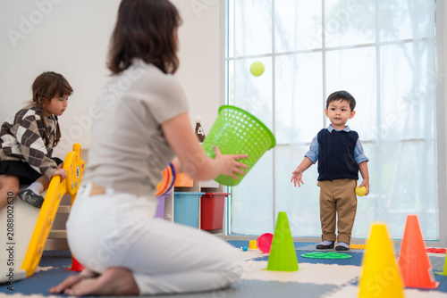 Children play with colorful toys in a bright room as a woman helps them learn and have fun together