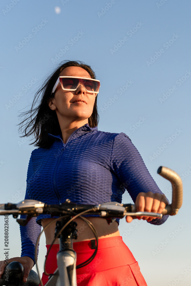 Obraz premium Woman bicycle summer outdoors exercising on a sunny day with clear blue sky backdrop for healthy lifestyle sports concept