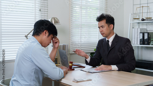 Asian lawyer consulting stressed male client in office for legal advice