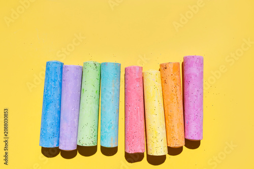 Colorful chalk sticks arranged on bright yellow background with wide copy space for creative layouts. Chalk supports education, classroom promotion, school branding and marketing materials 