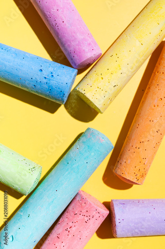 Macro shot of multicolored crayons for drawing and creativity. Crayons on a yellow background, top view. Materials for preschool and school education, children's drawing, and fun leisure activities.