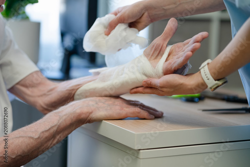 Mobility limitations and activity restrictions after arm fracture recovery period, bandage on patient hand with nurse watch visible during healing and rehabilitation in hospital clinic setting