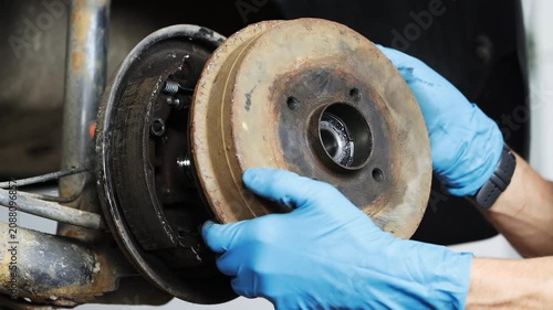 A car mechanic is repairing a car's brake system, close-up of the brake drum.