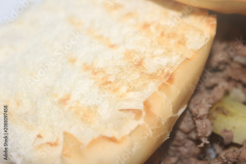 toasted bread with minced meat and sweet potato details. High angle close-up of a rustic dish with grounded beef. meal featuring crisp bread and sweet potatoes. toasted bread with minced meat.