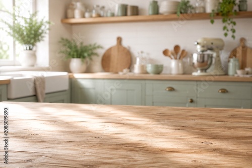 Rustic Wooden Tabletop in Bright Farmhouse Kitchen Empty rustic wooden tabletop with softly blurred farmhouse kitchen, sage cabinets, plants, and warm sunlight for product display