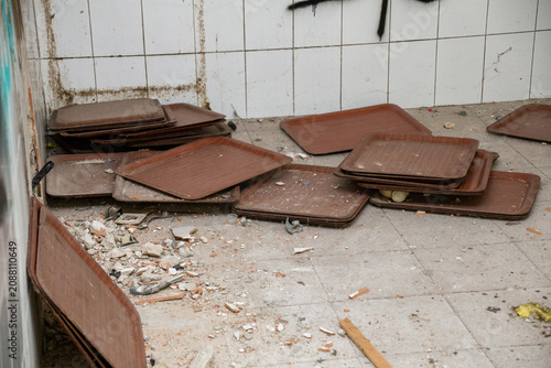 Fotografie Abandoned cafeteria trays scattered on a debris-filled floor in a neglected buil