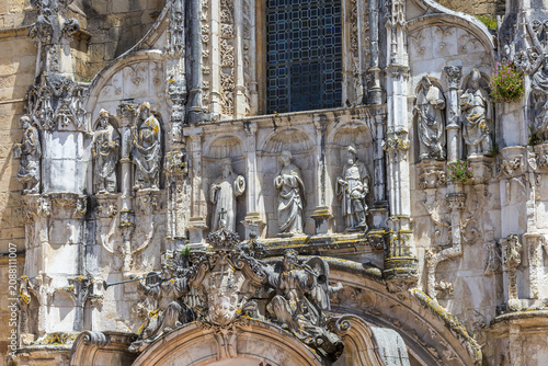 a lavishly decorated Manueline-style limestone facade, showcasing intricate sculptures of religious figures, saints