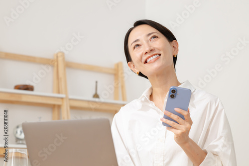 スマホを見ながらパソコン操作する女性