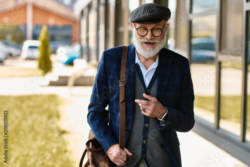 Fotografia A fashionable senior gentleman strolls outside a contemporary building, exuding charisma in autumn attire