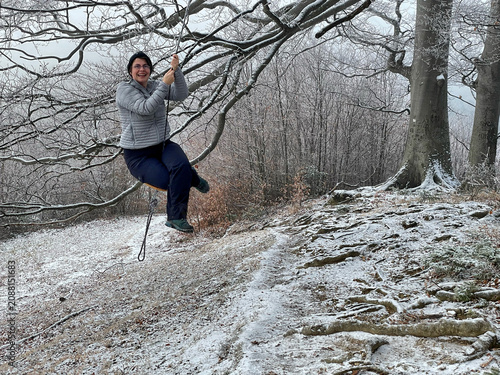 Photos Frau schaukelt lachend im Winter auf einer Schaukel, die an einem Ast eines vers