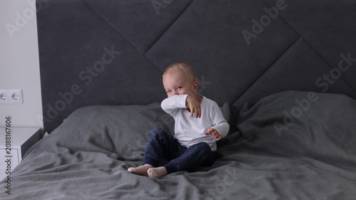 Happy smiling blonde child is having fun jumping on a bed. 4K