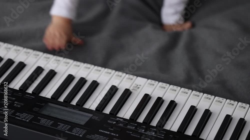 Smiling little child pushes buttons on electric piano. 4k