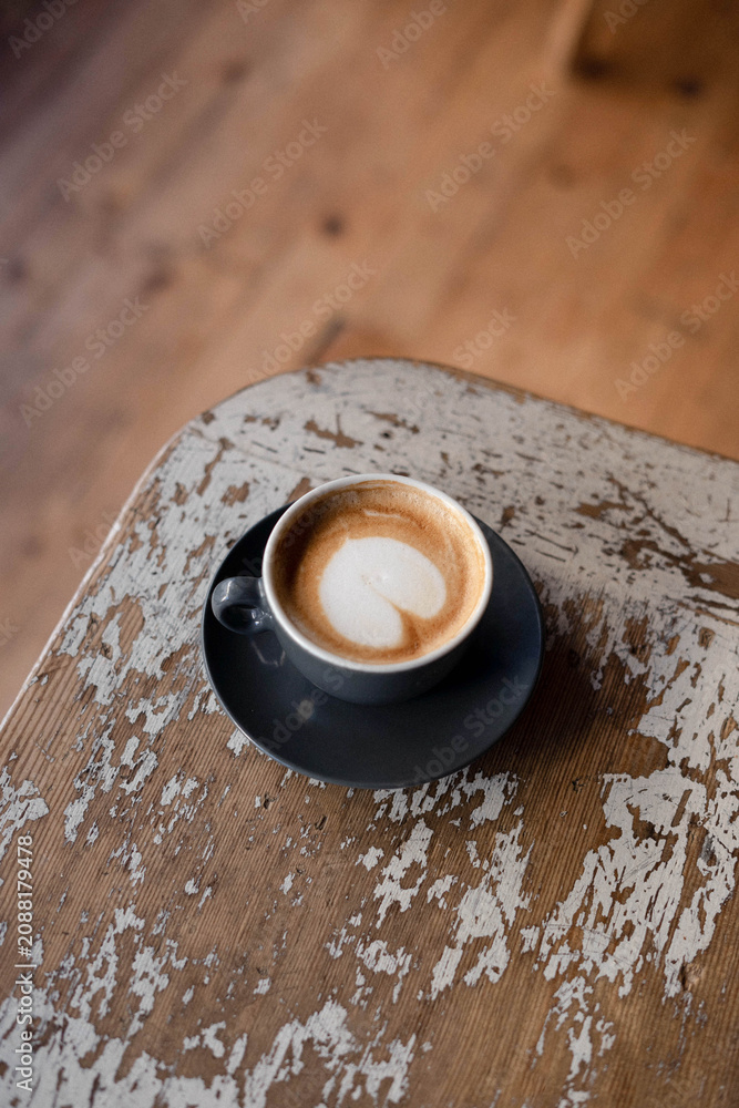 Fototapeta premium Cup of coffee on a rustic wooden table in cozy café