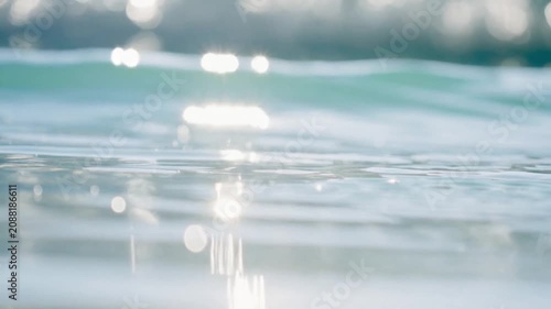 Close up of clear water surface with sunlight reflections and soft blue background in nature