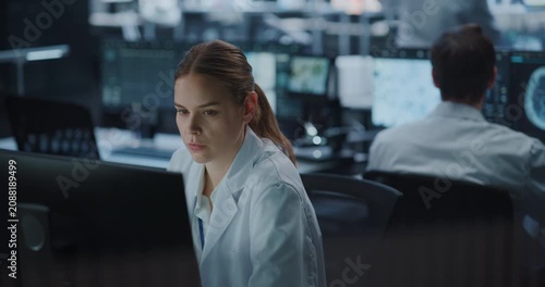 Portrait of Female Scientist Works Intently on a Computer in a High-tech Medical Research Facility While a Male Colleague Studies Brain Scan Data Nearby, Leveraging Ai Technology for Drug Development.