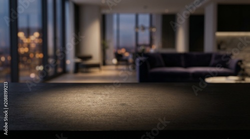 Dark wooden surface close-up with a blurred penthouse apartment background, city lights visible through large windows at dusk.