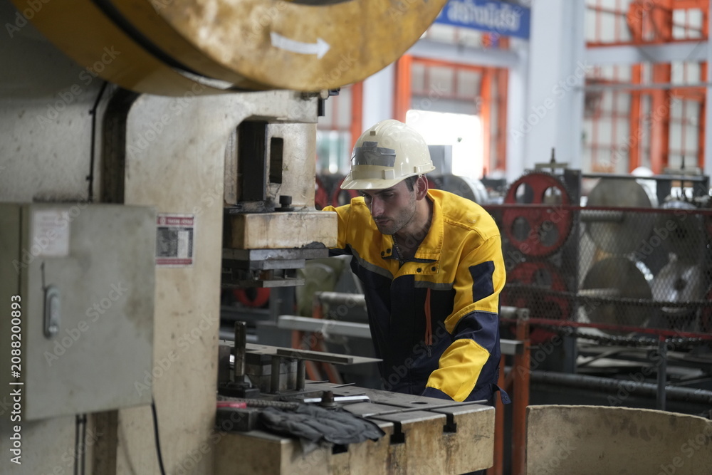Fototapeta premium Worker operates a machine in a factory setting during daytime hours