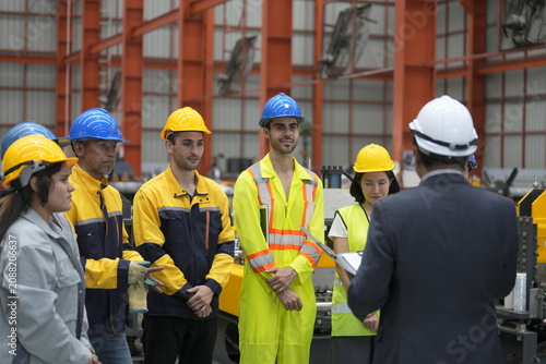 Tableau sur toile Workers listen to a safety briefing led by a supervisor in a factory setting dur
