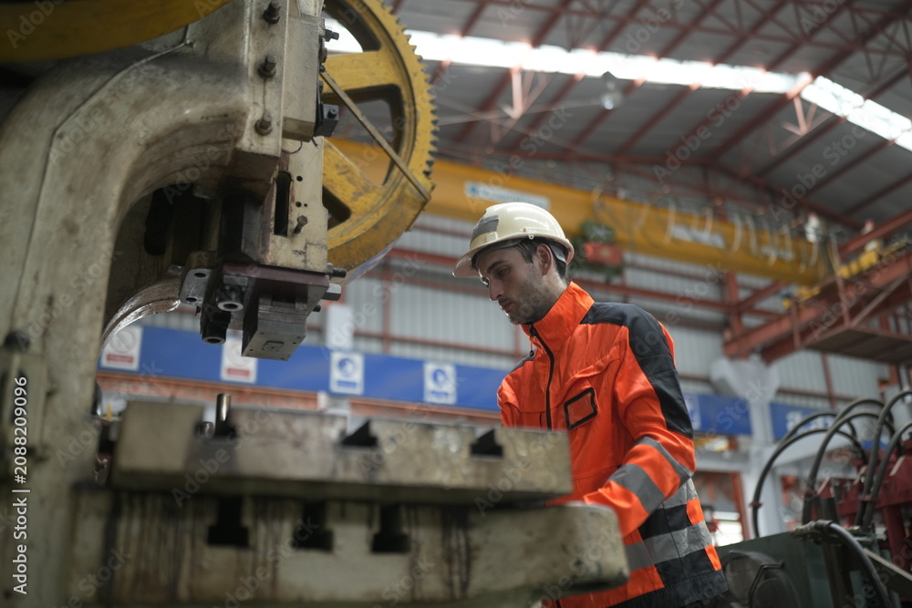 Fototapeta premium Worker operates machine in factory during daytime in industrial area