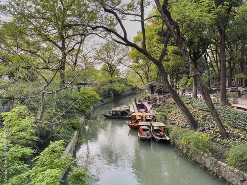 Wooden boats moored on spring canal with flowers at Tiger Hill, Suzhou, Jiangsu, China