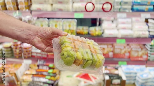 Male Hand Holding a Pack of Colorful Ravioli or Dumplings Made from Colored Dough in Front of a Supermarket Refrigerated Display