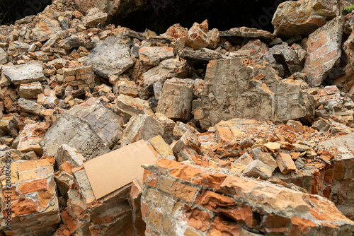 Debris covers the ground where a building has collapsed in an urban area. Bricks and stones are scattered all around