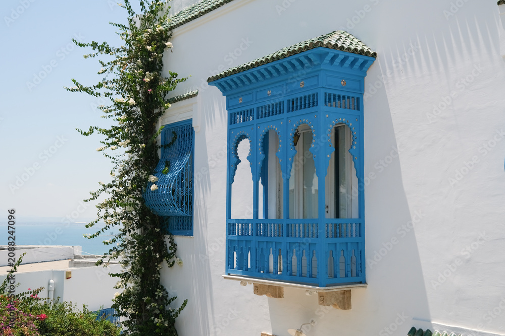 Fototapeta premium White Building with Blue Shutters and Bougainvillea in Mediterranean Town