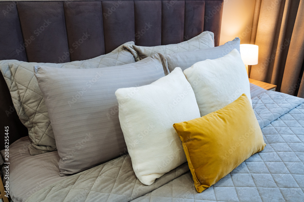 Fototapeta premium Comfortable cozy decor. Textured bedding with colorful accents. Relaxing setting featuring plush cushions and soft fabrics. Tranquil bedroom style with layered textiles and subtle hues