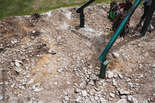 Green frames uphold tensioned cables for adventure above rocky landscape. Park staff readying zipline infrastructure amidst natural setting with safety tags clearly displayed