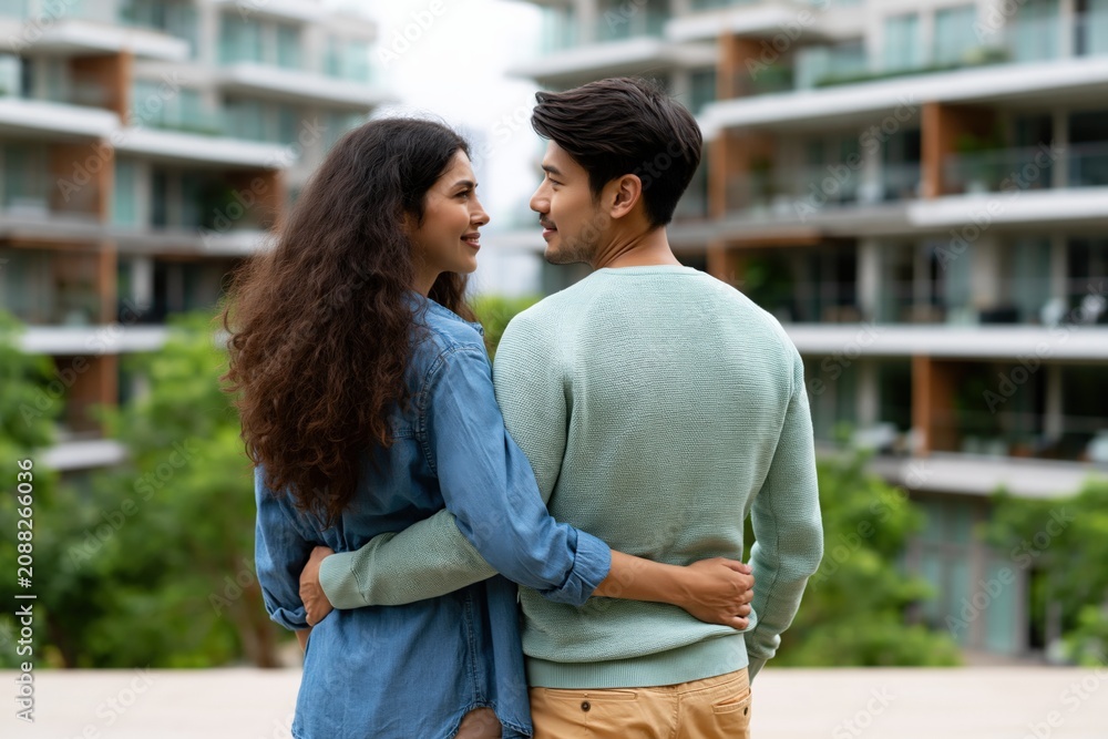 Fototapeta premium Couple holding each other facing city view with modern apartments for romantic relationship background and lifestyle design