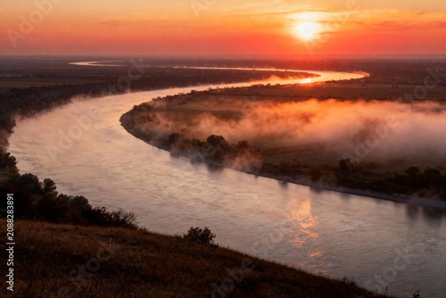 Sunrise over a winding river with mist rising from the water and surrounding landscape