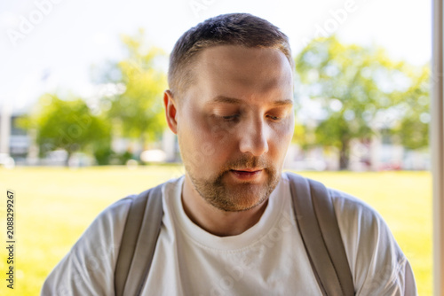 Young Caucasian man sitting at an outdoor terrace table, dipping a piece of bread and eating hot delicious soup on a sunny day.