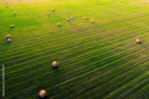 Fényképezés Aerial View of Round Hay Bales Scattered on Green Field at Sunset | Drone Shot o