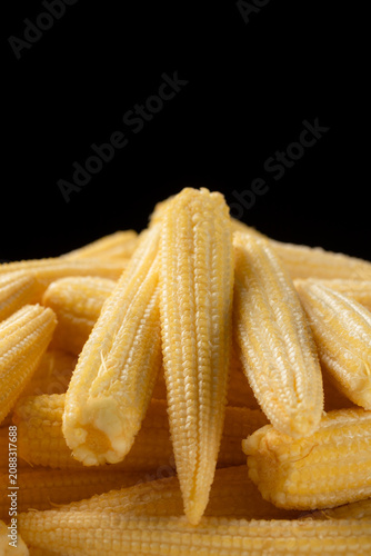 Pile of fresh raw yellow baby corns on a black background. Close-up
