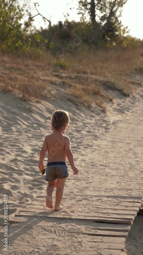 A small child walks along a wooden path. A toddler's summer adventures and the pure innocence of childhood