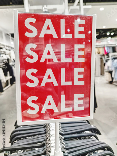 Red Sale Sign In Clothing Store Over Racks Advertising Discount Promotion And Seasonal Retail Savings.