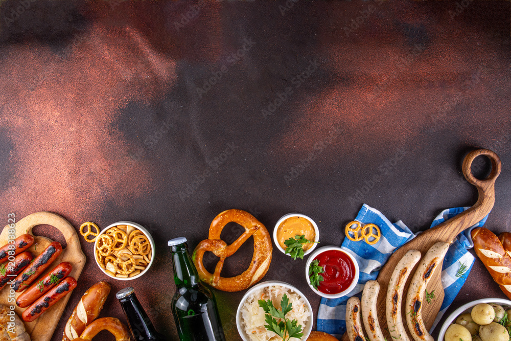 Fototapeta premium Oktoberfest picnic and barbecue food, bavarian party menu, bavarian sausages, pretzels, potato, sauerkraut, beer bottles, with picnic basket, checkered napkin tablecloth, Oktoberfest festive ribbon