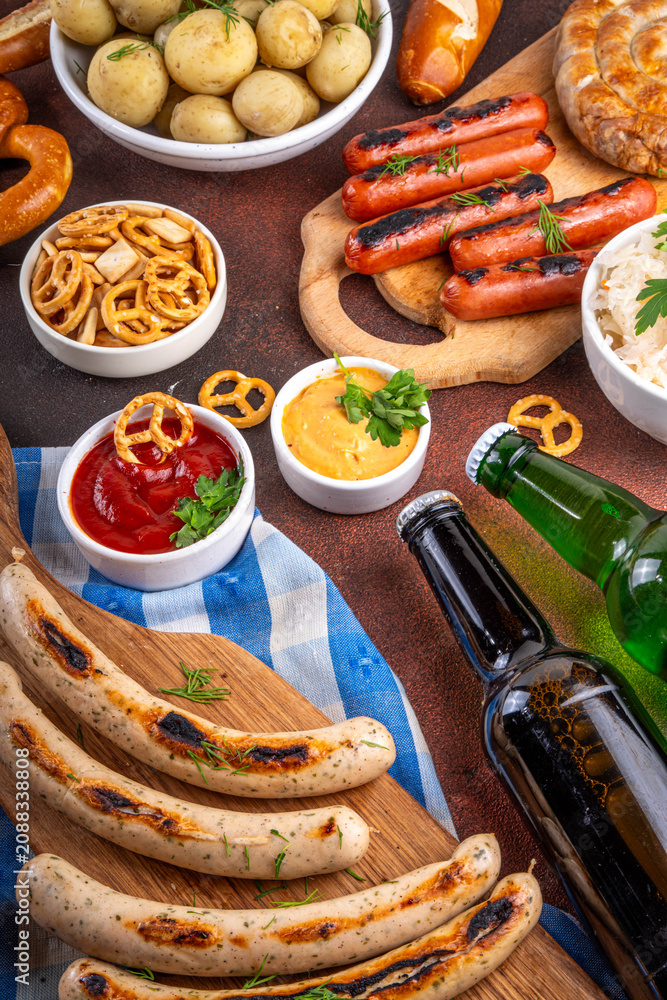Fototapeta premium Oktoberfest picnic and barbecue food, bavarian party menu, bavarian sausages, pretzels, potato, sauerkraut, beer bottles, with picnic basket, checkered napkin tablecloth, Oktoberfest festive ribbon